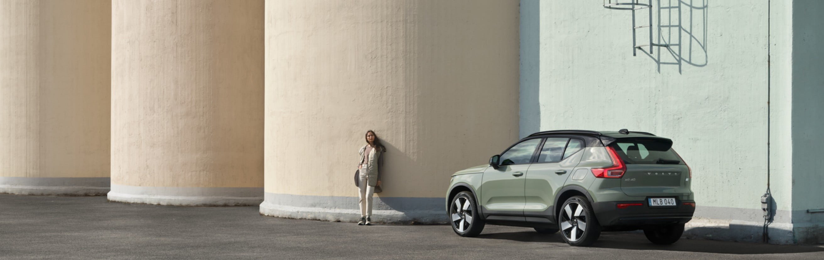 Frau läuft weg von einem grauen Volvo.